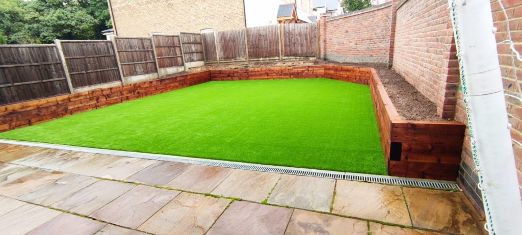 Artificial grass back garden with wooden surrounds.